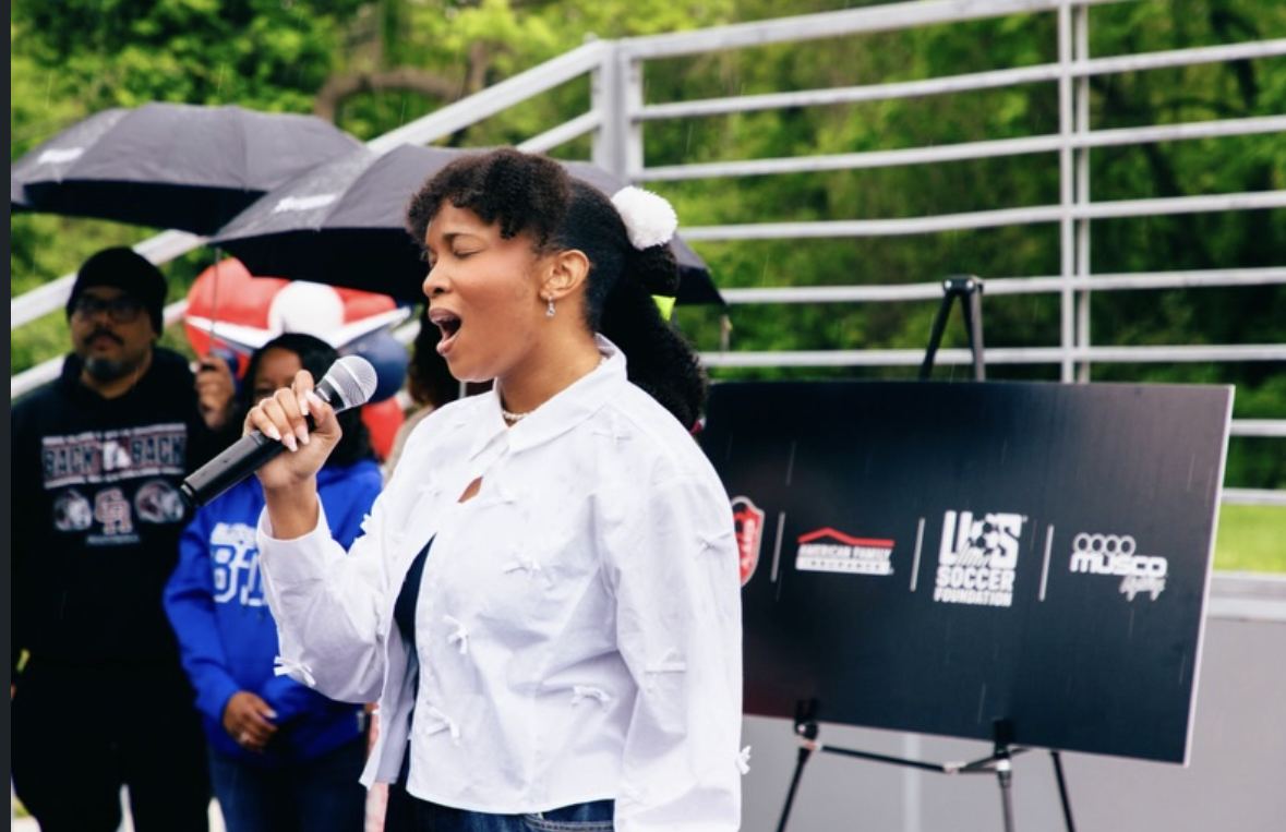 Florie singing into a microphone at the mini pitch opening