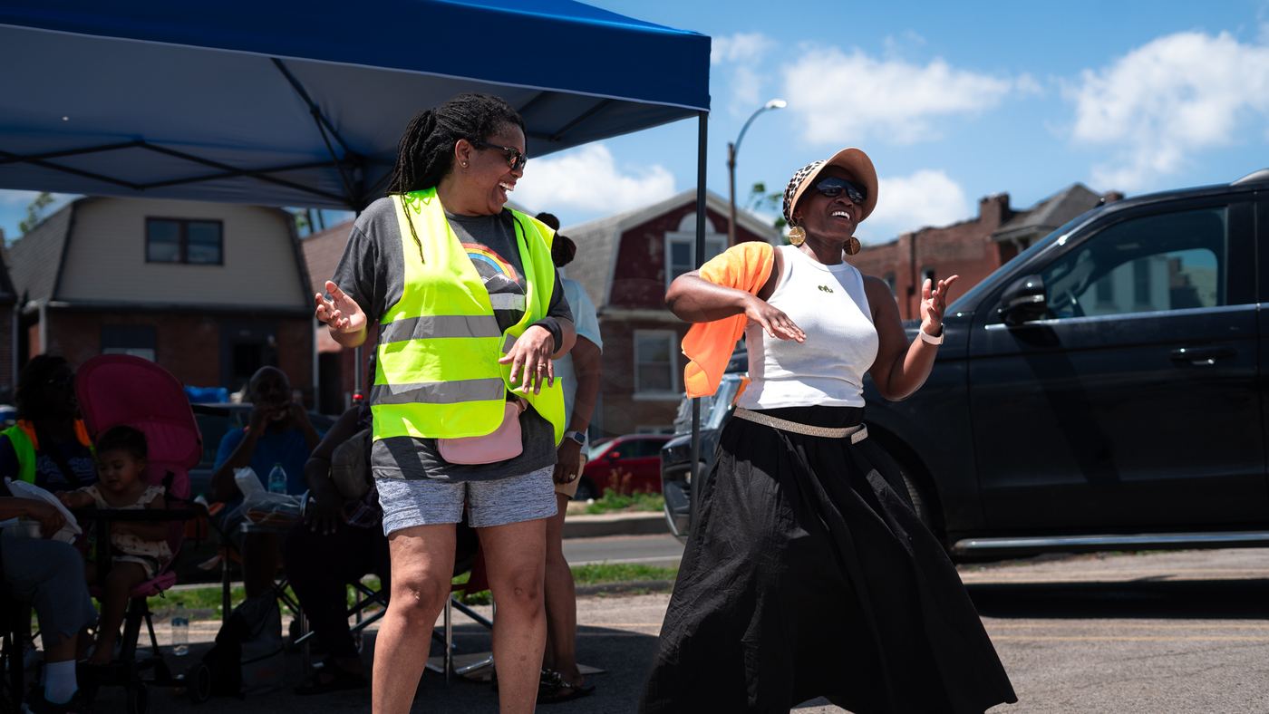 Two volunteers laughing and dancing beside a tent