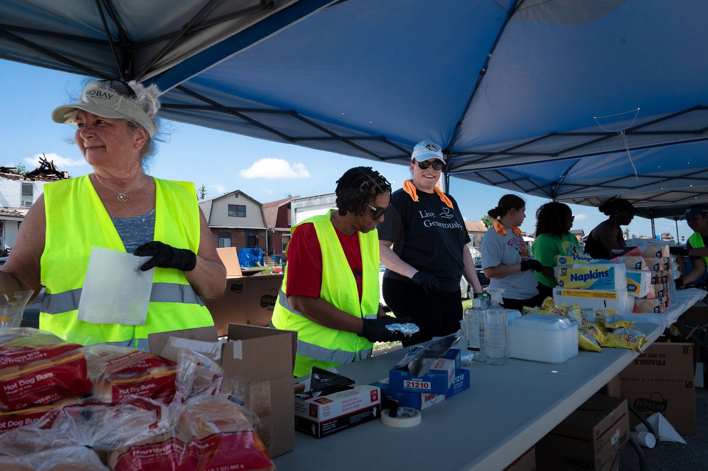 Volunteers smiling while preparing meals at a long table