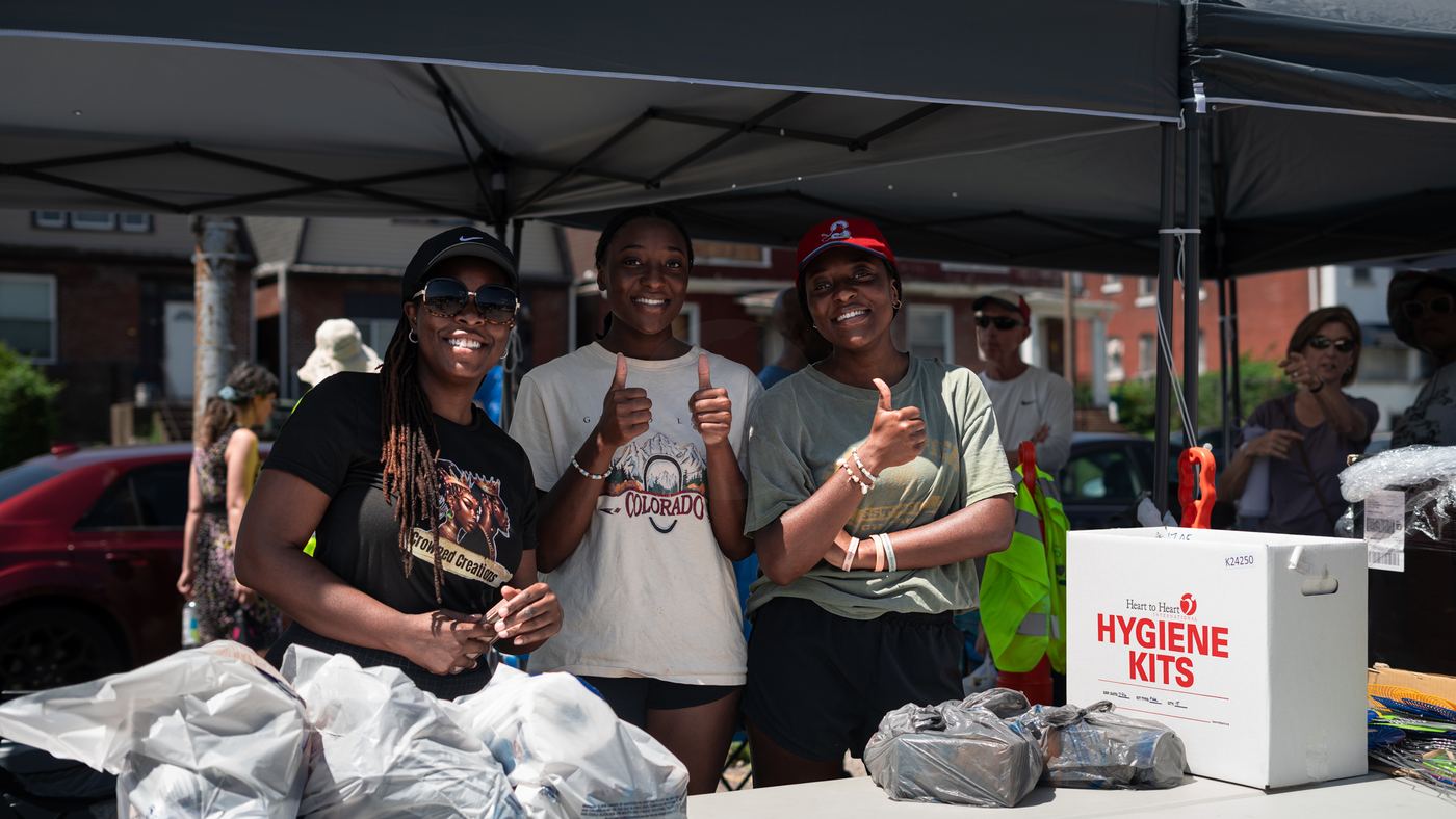 Three volunteers smiling with thumbs up