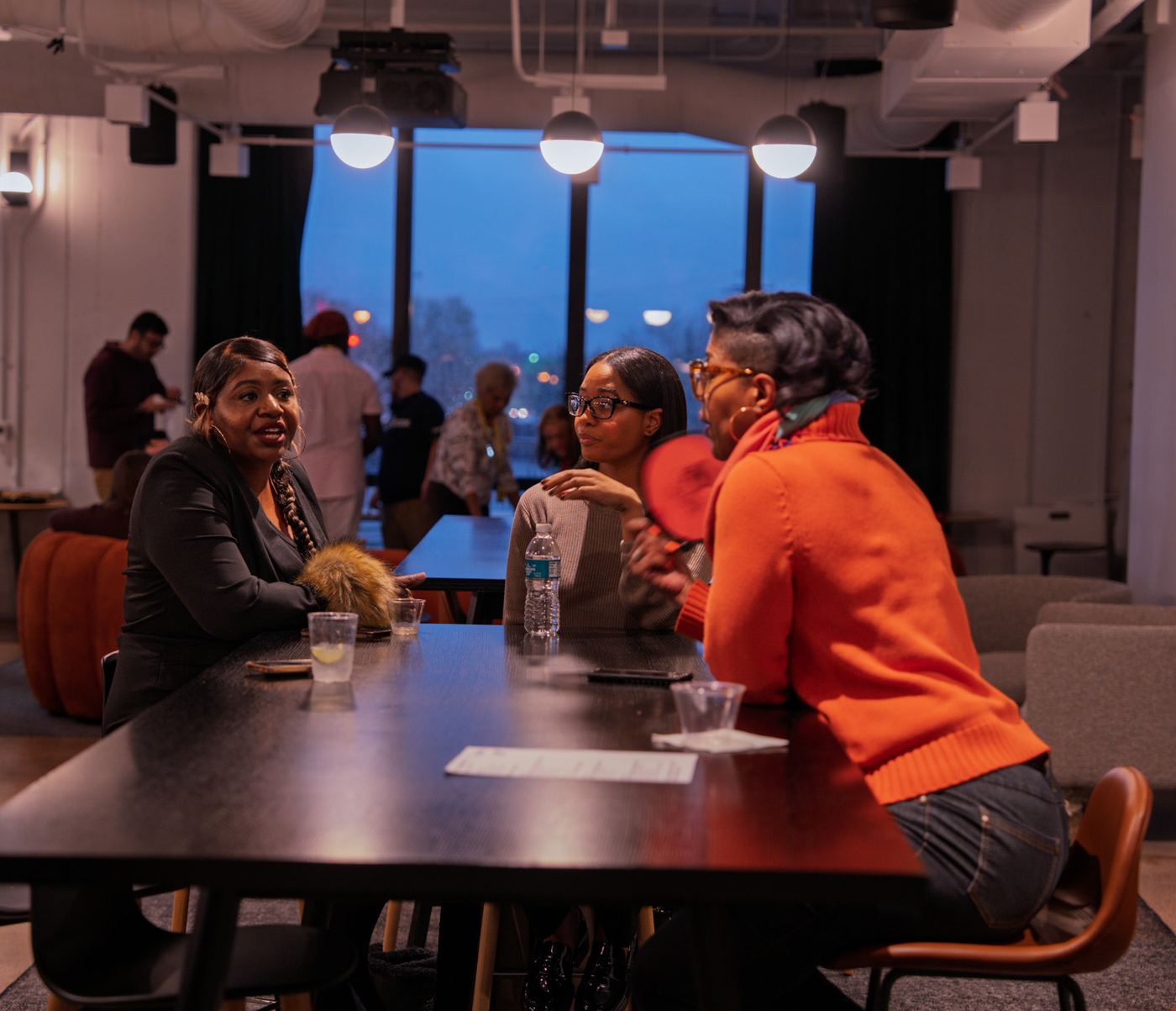 Three women in conversation at a long table